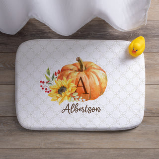 Autumn-themed bath mat with a floral pumpkin design, personalized with an initial and name in elegant script.