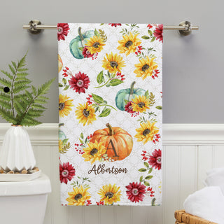 Bath towel with a fall floral pumpkin pattern, personalized with an initial and name in elegant script.