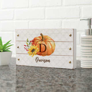 Wood block sign with a fall floral pumpkin design, personalized with an initial and name in elegant script.