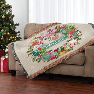 Fringe throw blanket featuring a whimsical ornament wreath design, personalized with a name in the center